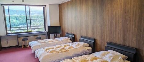 A hotel room with two beds, a large window with a view, a desk, and a chair.