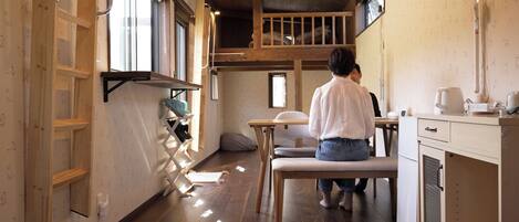 A compact kitchen with wooden cabinets, a bench, and a dining table.