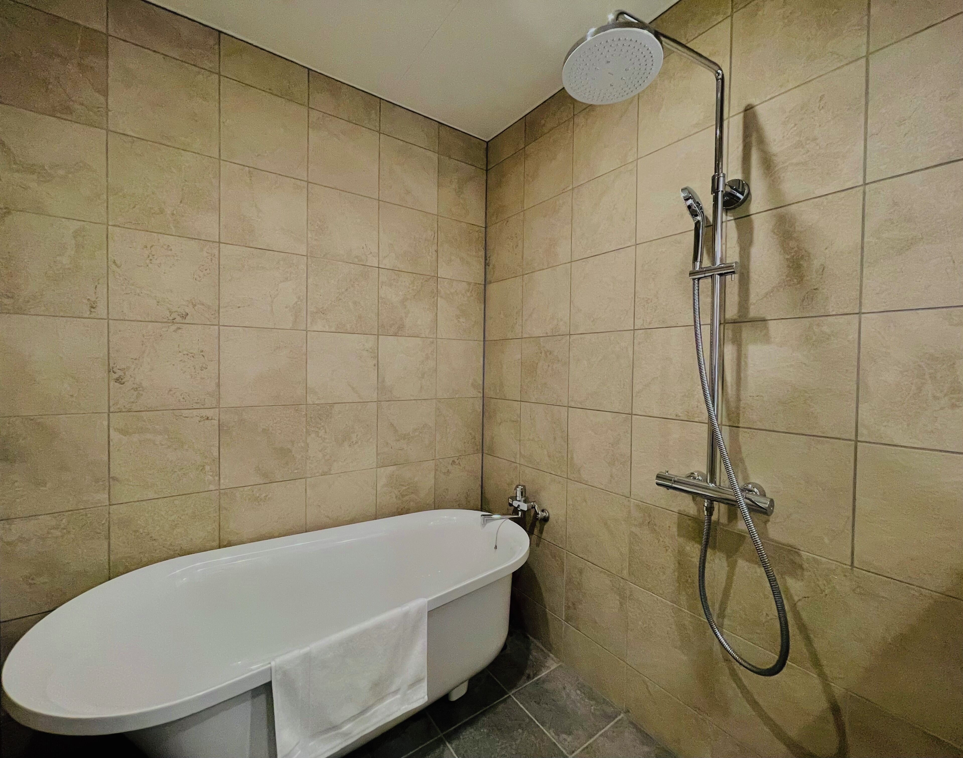 A bathroom with a bathtub, a showerhead, and a toilet.