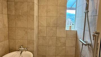 A bathroom with a bathtub, shower, and a window with a view.