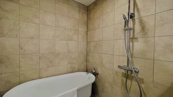 A bathroom with a bathtub, a showerhead, and a toilet.