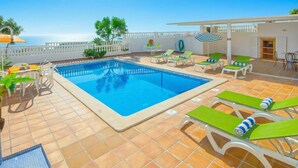 A swimming pool with lounge chairs, a table, and a view of the sea. - Your perfect Algarve retreat with a pool (Sao Rafael)