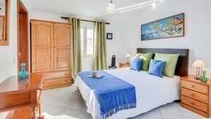 A bedroom with a large bed, wooden wardrobe, a painting, and a nightstand with a lamp. - Your perfect Algarve retreat with a pool (Sao Rafael)