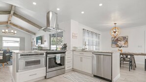 Une cuisine moderne avec des meubles blancs, des appareils en acier inoxydable et un îlot central.