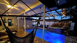 Un espace piscine agrémenté d’un hamac, de chaises longues et d’un mur en pierre.