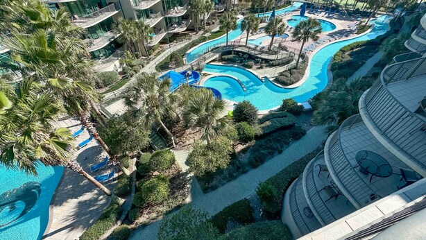 Een resort met diverse zwembaden, palmbomen en een moderne gebouwstructuur.