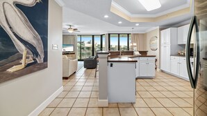 Een moderne keuken met witte kasten, een centraal eiland en een groot raam met uitzicht op de stad.