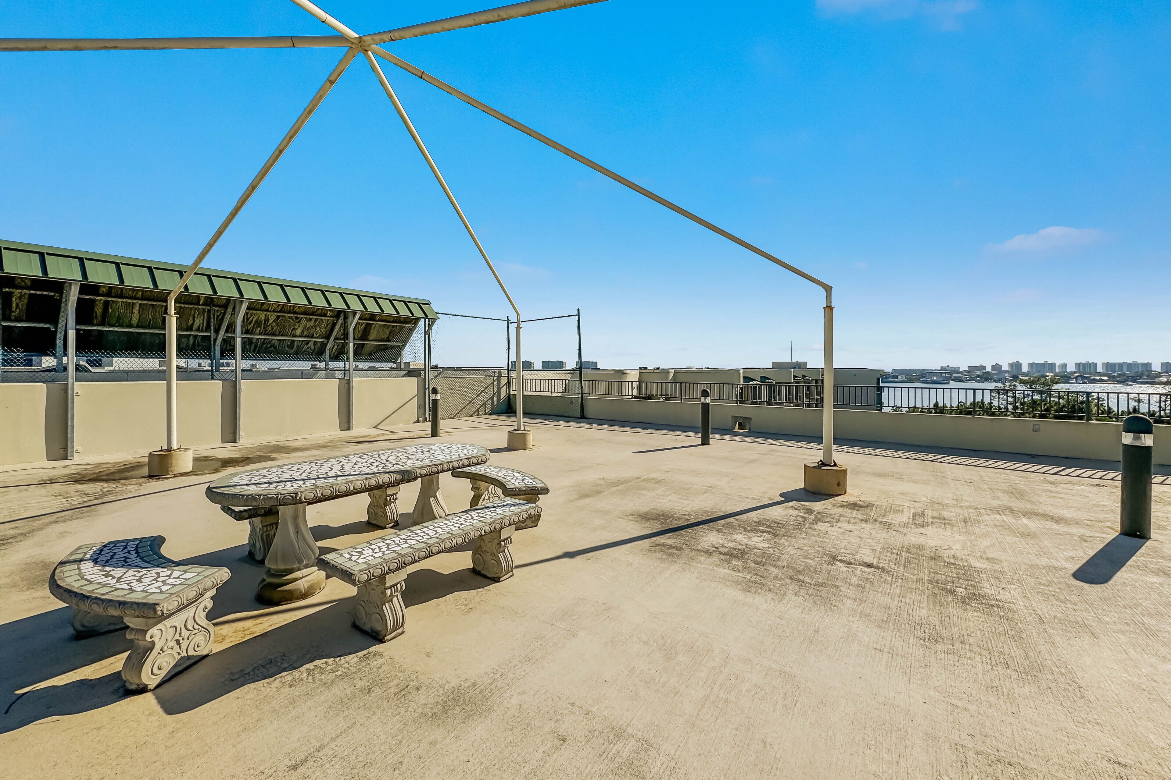 A rooftop terrace with a picnic table and benches, a covered seating area, and a view of the city skyline.