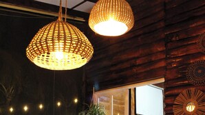 A wooden dining table with two wicker chairs, a bowl of fruit, and hanging wicker lamps. - Charming 3-bedroom beach cabin with Starlink WiFi, AC in enchanting Tamanique (Tamanique)