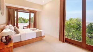A bedroom with a large bed, a nightstand, a lamp, and a view of greenery through large windows.