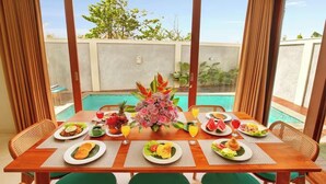 A dining table set for four with plates of food, a vase of flowers, and drinks.