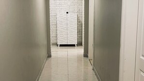 A hallway with a tiled floor, a patterned ceiling, and a white door on the right. - Amazing 3-bedroom apartment with WiFi in Ajman (Ajman)
