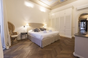 A bedroom with a bed, bedside lamps, a wicker chair, and a wardrobe.