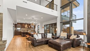 A spacious living area with a large sectional sofa, a wooden coffee table, and a dining area with a kitchen in the background.