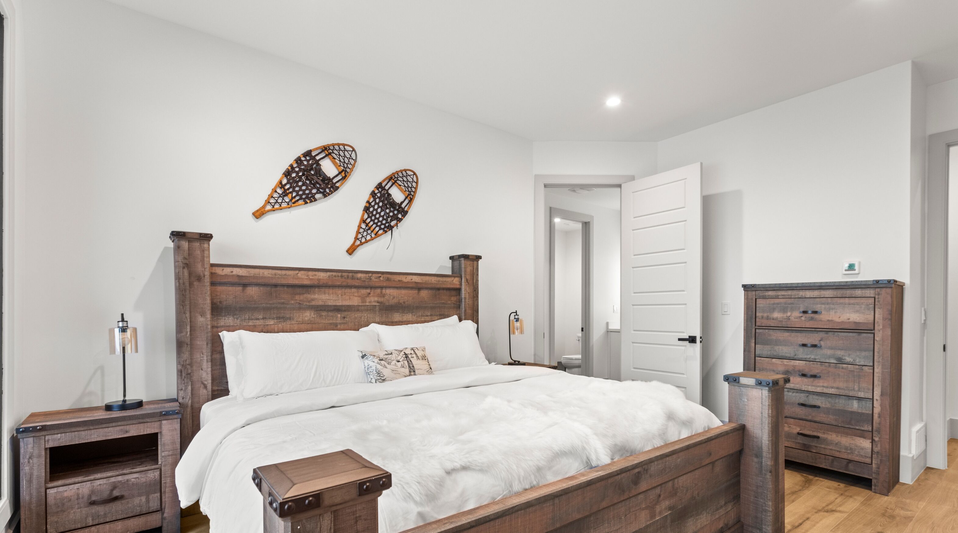 A bedroom with a wooden bed, two nightstands, a dresser, and a white door.