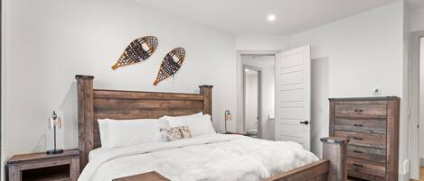 A bedroom with a wooden bed, two nightstands, a dresser, and a white door.