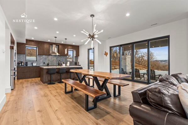 A modern kitchen with wooden countertops, a central island, and a dining area with a wooden table and benches.