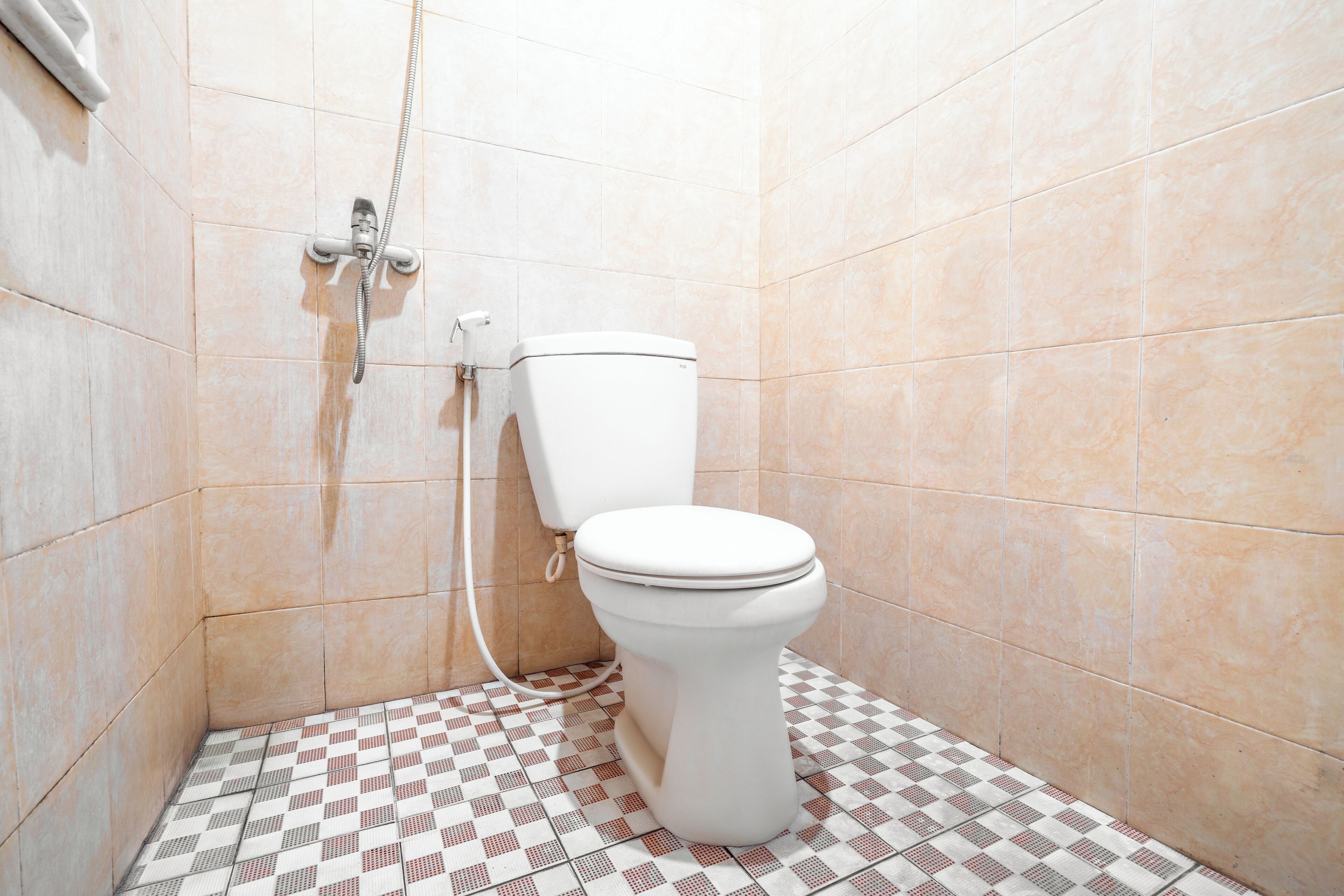A small bathroom with a toilet, a shower, and a tiled floor.