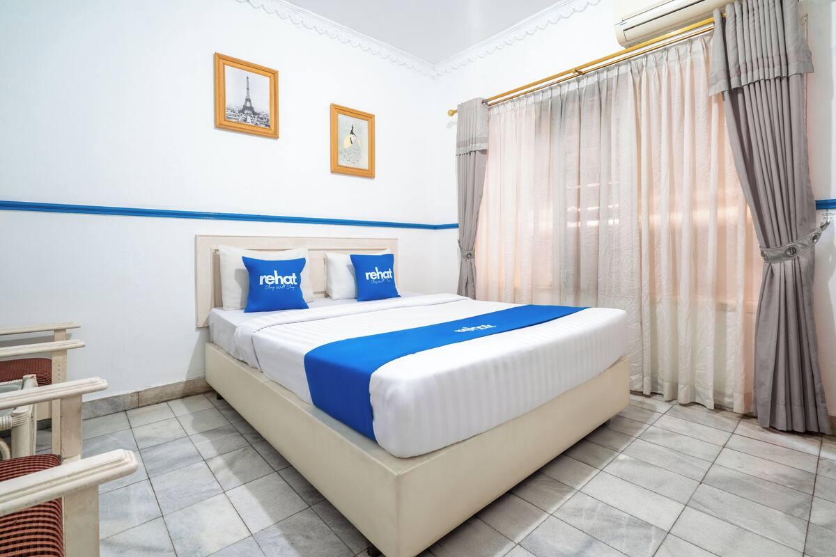 Ein ordentlich eingerichtetes Hotelzimmer mit einem großen Bett, einem Sessel und einem kleinen Tisch.