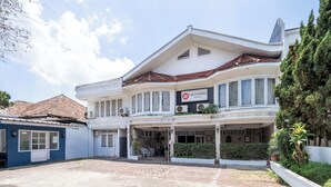 Ein Hotel mit überdachter Eingangsparte, Außenbestuhlung und einem gepflegten Garten.