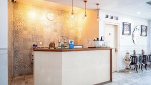 Eine Küche mit einer zentralen Kochinsel, einem gemusterten Rückspritzschutz, hängenden Pendelleuchten und einer Uhr an der Wand.