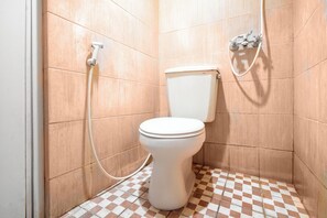 Baño con inodoro, ducha y piso de baldosas de cuadros.