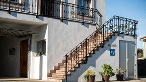 A building with a staircase leading to a balcony, a door labeled "EL ANGEL", and potted plants. - El Angel Vacation Home (Piñeres De Pria)