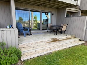 A covered patio with a table and chairs, a blue chair, and a small plant. - 2026 Remodeled waterfront 1 bedroom escape on Lake Michigan in Glen Arbor MI (Glen Arbor)