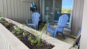 A deck with two chairs, a small garden, and a sliding glass door leading to a room. - 2026 Remodeled waterfront 1 bedroom escape on Lake Michigan in Glen Arbor MI (Glen Arbor)