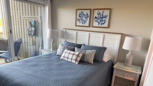 A bedroom with a large bed, a nightstand with a lamp, and two wall-mounted paintings. - 2026 Remodeled waterfront 1 bedroom escape on Lake Michigan in Glen Arbor MI (Glen Arbor)