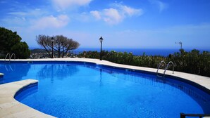 Une piscine d’un bleu éclatant, à bords incurvés, entourée d’une terrasse en pierre.