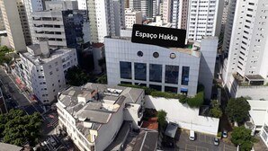 Un edificio moderno con fachada plana y grandes ventanales, rodeado de edificios residenciales de gran altura.