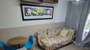 Una habitación con un sofá, dos sillones, una mesa de madera y una obra de arte enmarcada en la pared.