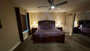 A bedroom with a bed, two bedside tables with lamps, a ceiling fan, and a door leading to another room. - The Moonlight Express (Parker)