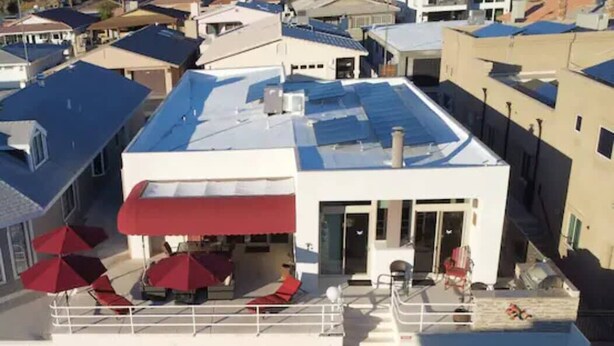 A building with a red awning, a covered outdoor seating area with umbrellas, and a staircase leading to the entrance. - Kastle on the Keys, Private Dock (Parker)