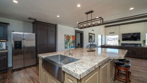A modern kitchen with a large island, stainless steel appliances, and a built-in TV. - Eagles Lair, Pool & Views! (Parker)