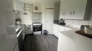 A compact kitchen with white cabinets, a built-in oven, a microwave, and a toaster.