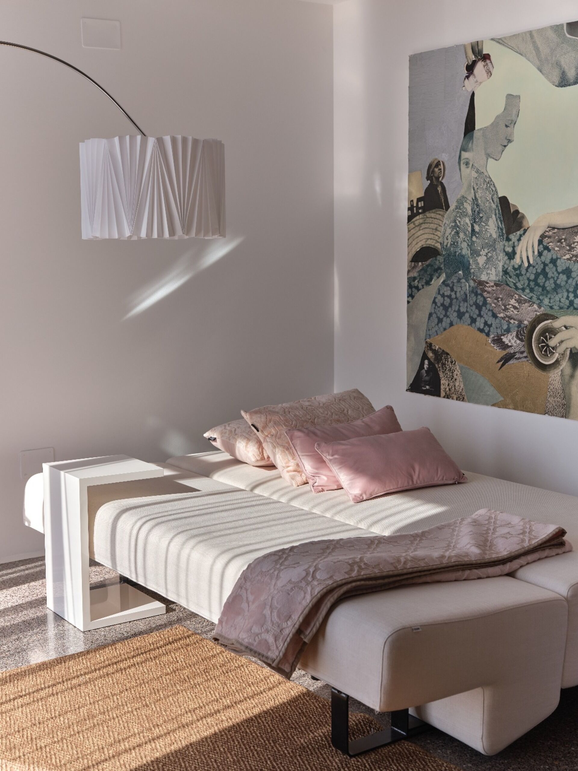 A modern bedroom with a bed, bedside tables, a wall-mounted lamp, and a large painting.