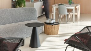 Un área de estar moderna con sofá, mesa redonda y sillas.