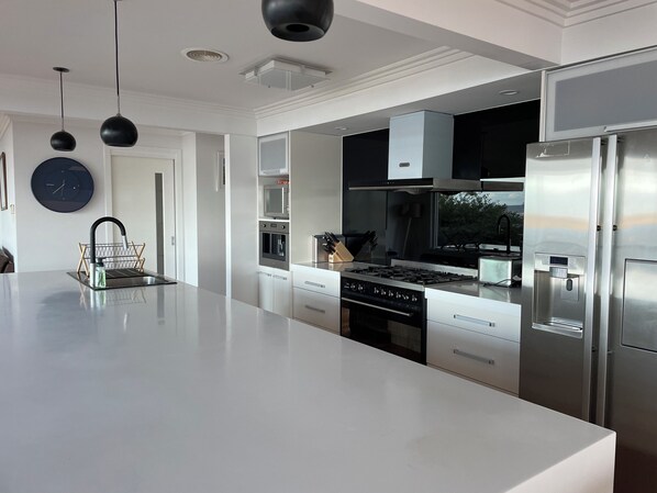 A modern kitchen with a large island, stainless steel appliances, and pendant lighting. - Lipscombe Escape panoramic views luxury and space (HOBART)