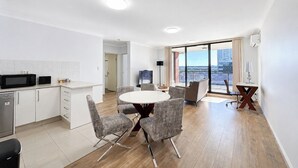 En modern lägenhet med kök, matplats och stora fönster med utsikt över staden.