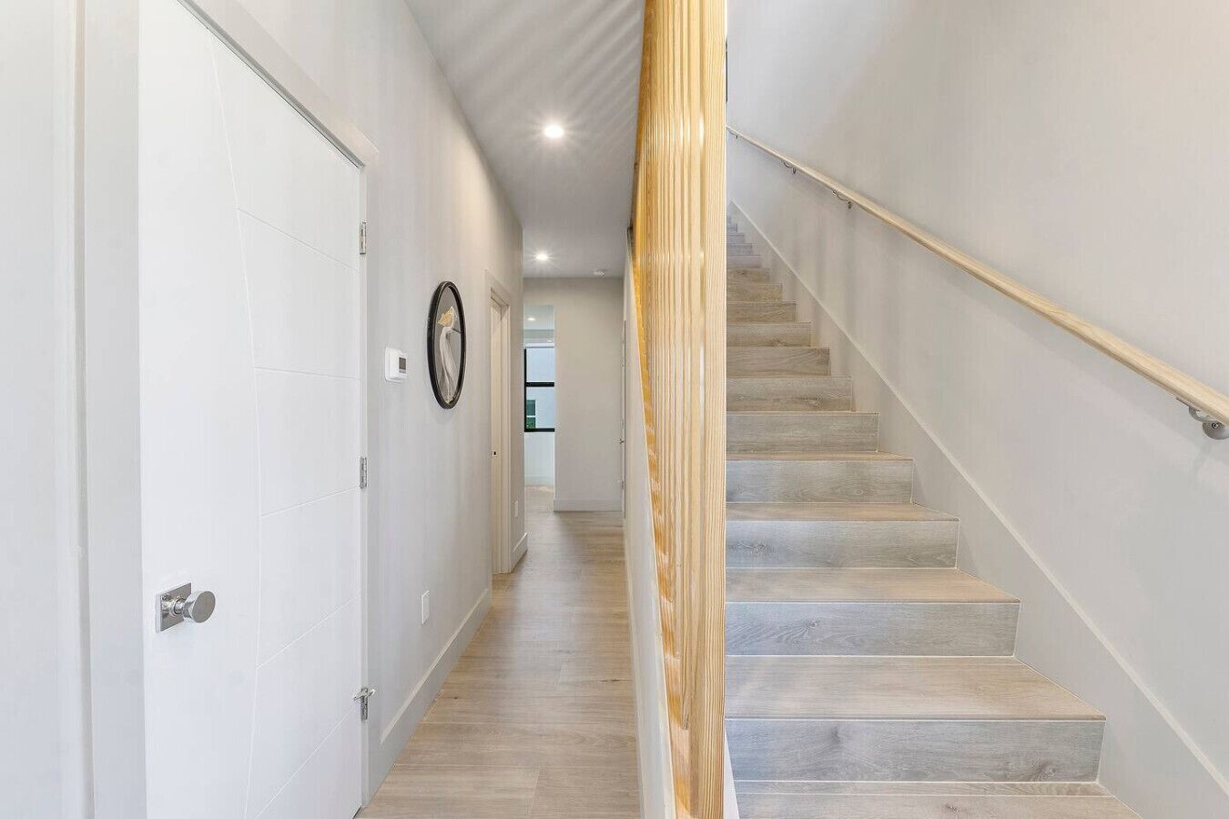 A modern hallway with a wooden staircase leading to a second floor.