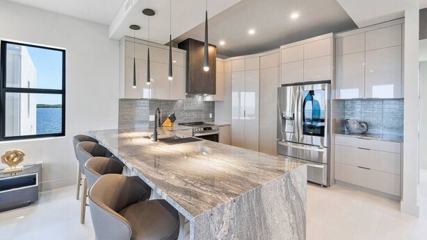 A modern kitchen with a large island, stainless steel appliances, and a view of the water. - New Oceanside Paradise with Pool and Waterfront Views! (Key Largo)
