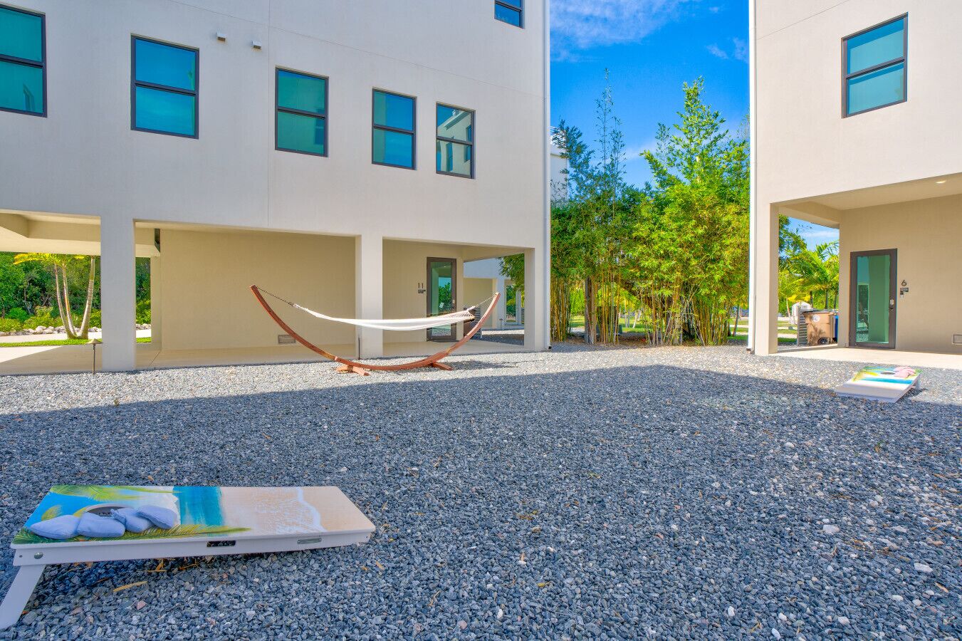 Un edificio moderno con un patio de grava, una hamaca y un cuadro sobre una mesa.