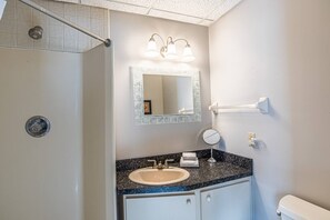 Ein Badezimmer mit Waschbecken, Spiegel, Handtuchhalter und Dusche.