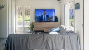 Un soggiorno con televisore, divano e una pianta.