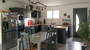 Una cucina moderna con elettrodomestici in acciaio inossidabile, un tavolo da pranzo con sedie e un'ampia finestra che garantisce luce naturale.