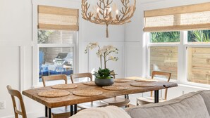 A dining area with a wooden table, woven placemats, a potted plant, and a chandelier. - Coastal Chic, Heated Pool, Beachside, Custom Bunk Room (St. Augustine)