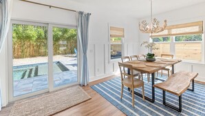 A dining area with a wooden table, benches, and a chandelier. - Coastal Chic, Heated Pool, Beachside, Custom Bunk Room (St. Augustine)