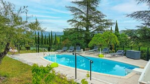 A swimming pool with lounge chairs and a small table, surrounded by greenery and trees. - Awesome home in Saint-Laurent-du-Verdo (Saint-Laurent-du-Verdo)
